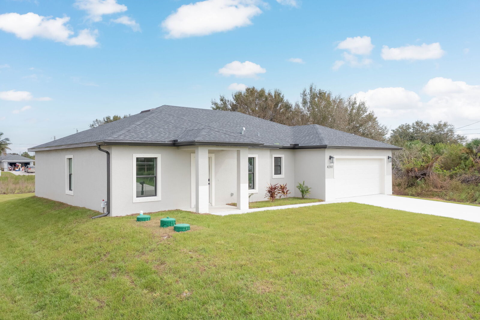 Brand-new single-story home with a wide grass yard under a blue Florida sky